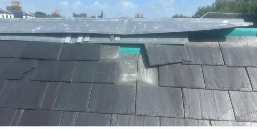 Storm-damaged ridge with lifted lead and missing slates, before repair