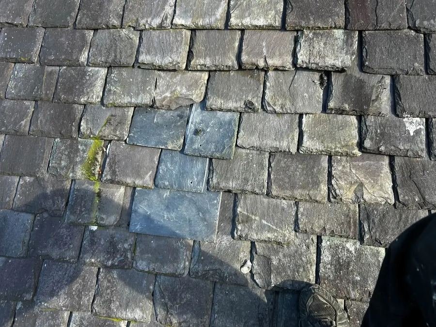 New slates fitted into an older slate roof, matching the surrounding courses