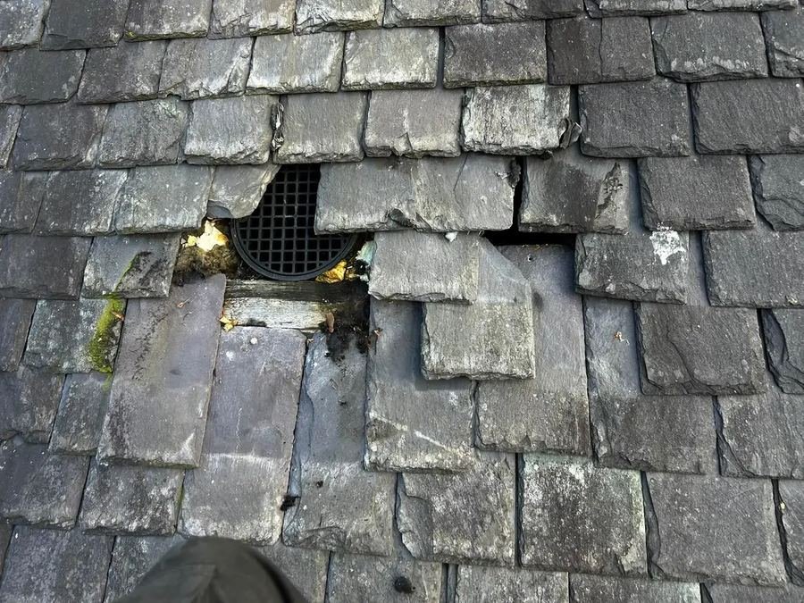 Blocked and broken slates around a roof vent on a Glasgow tenement before repair